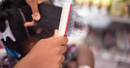 A wide-tooth comb being drawn through textured hair
