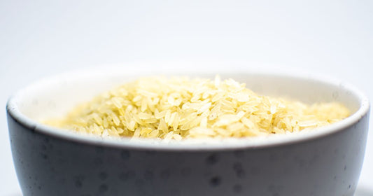 A bowl of uncooked white rice on a light surface
