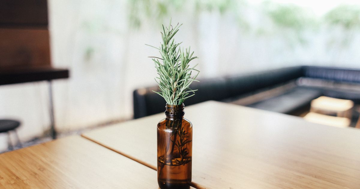 Rosemary sprigs in an amber glass bottle left out on a wooden table